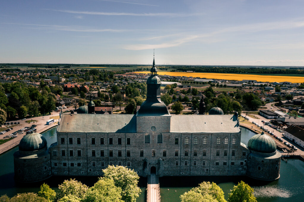 Vadstena slott från ovan med koppartak och torn, omgivet av Vätterns blå vatten och grönskande landskap