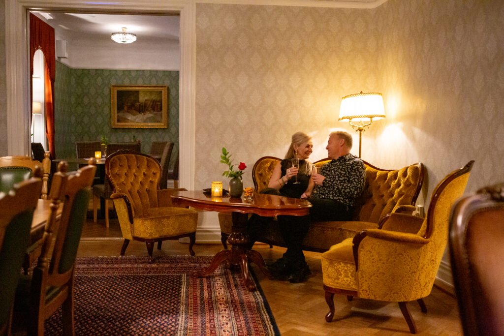 Par njuter av intim middag i elegant hotellobby med klassisk inredning och varm belysning