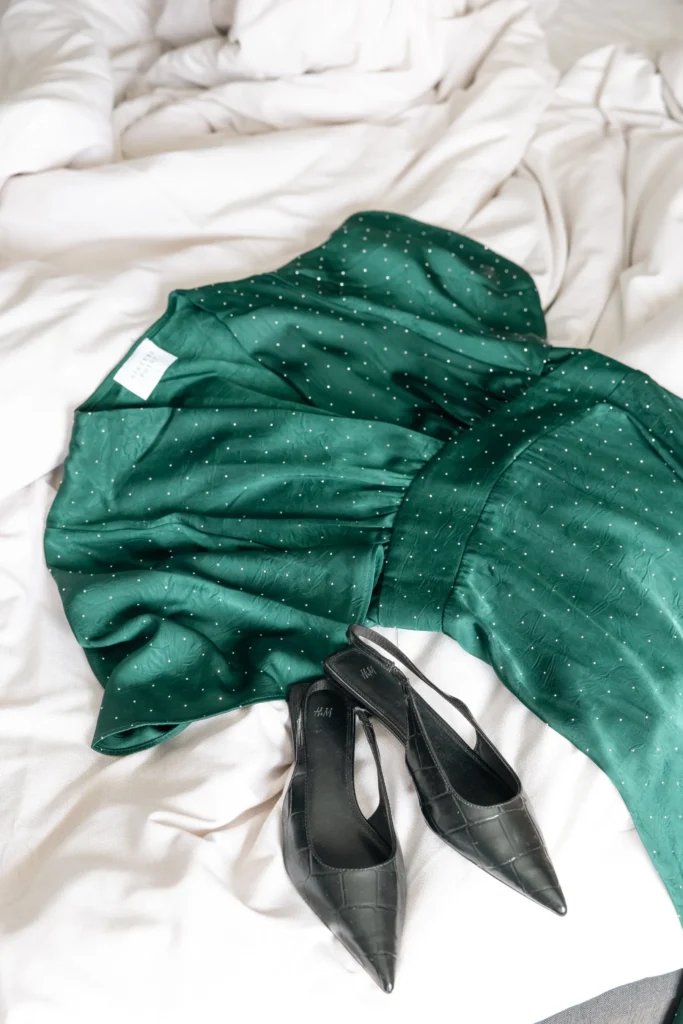 Green polka dot dress and black heeled shoes arranged on white linens, perfect for an elegant spa dinner
