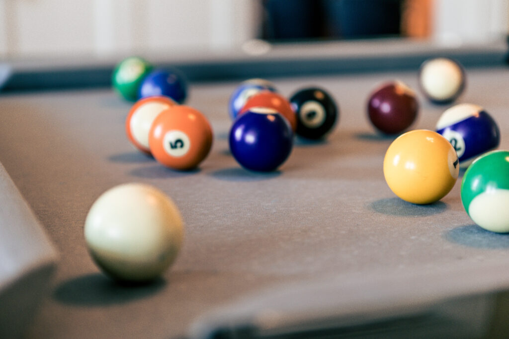 Biljardrum med färgglada poolbollar utspridda på grön bordsduk, avkopplande aktivitet på hotellet