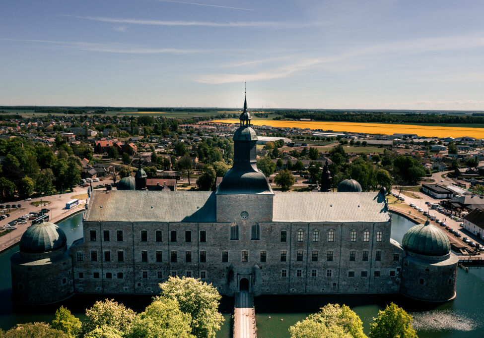 Vadstena slott från ovan med koppartak och torn, omgivet av Vätterns blå vatten och grönskande landskap
