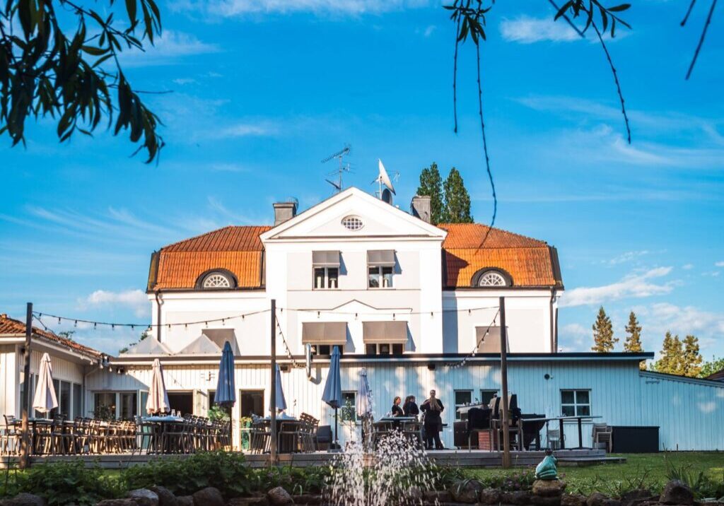 Starby Spa & Hotells huvudbyggnad med orangerött tegeltak och vit fasad, omgiven av naturskön miljö vid Vättern